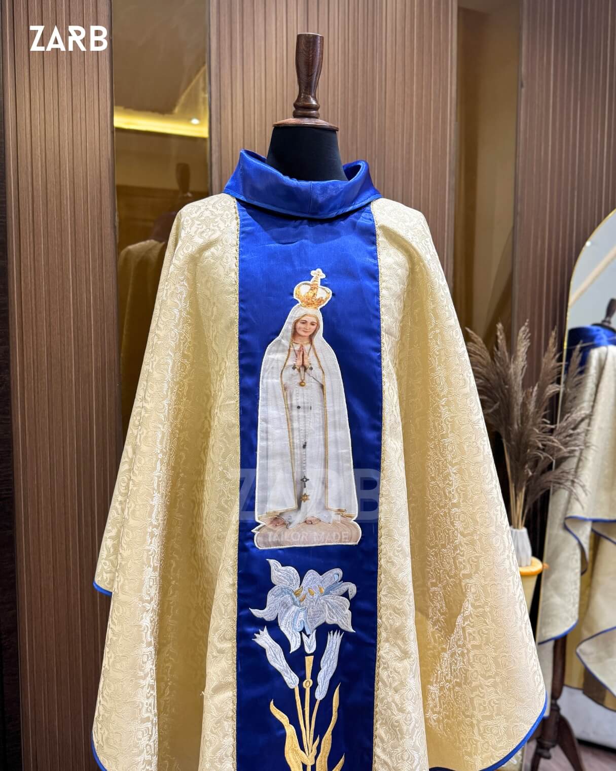 Ecclesiastical vestment with embroidered design on a mannequin against a wooden panel background.