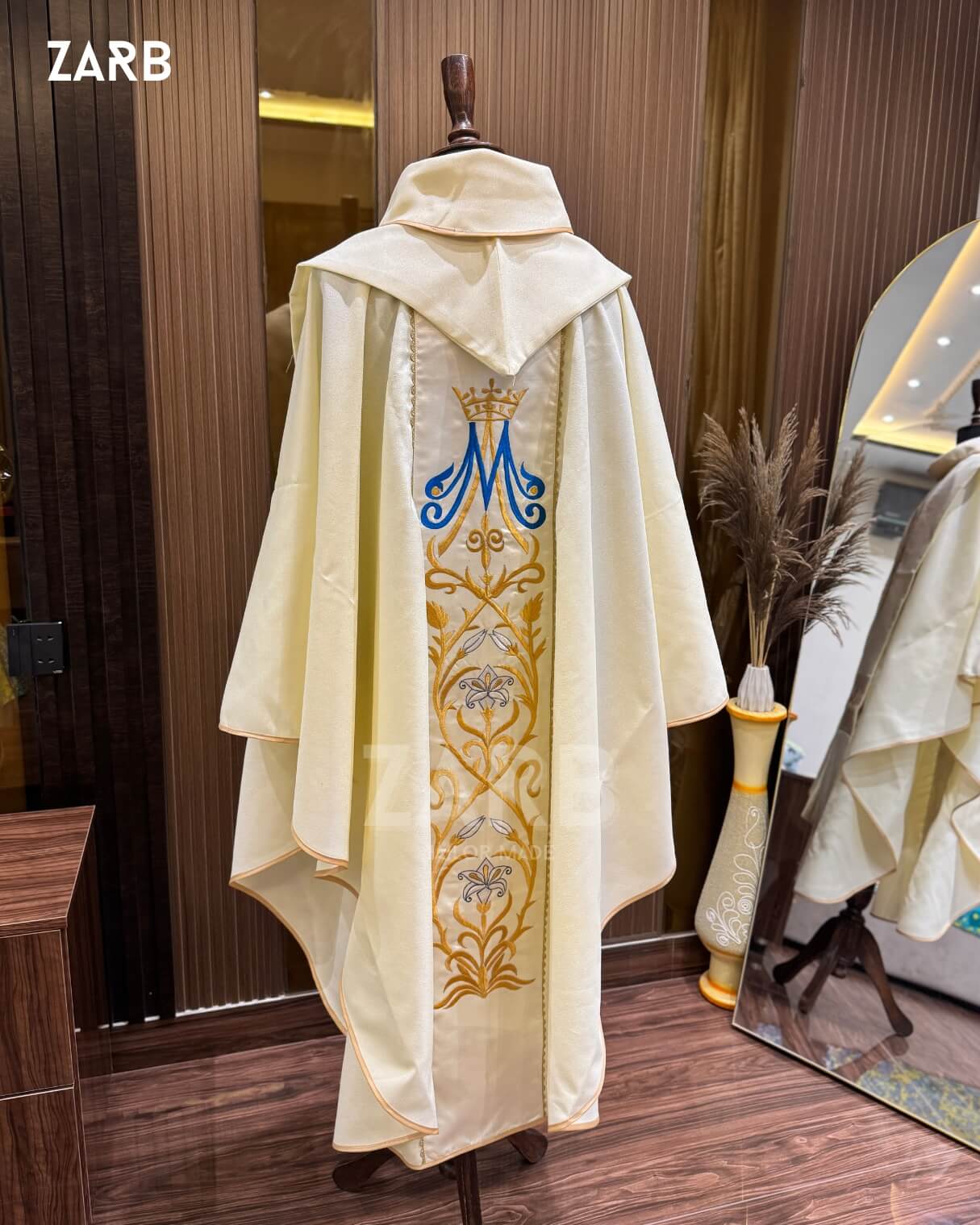 Ivory religious robe with embroidered design on a mannequin against a wooden background
