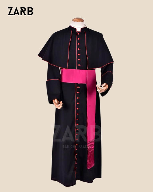 A mannequin displaying a custom black clergy cassock with magenta trim and buttons, along with a matching fascia (sash) tied around the waist.
